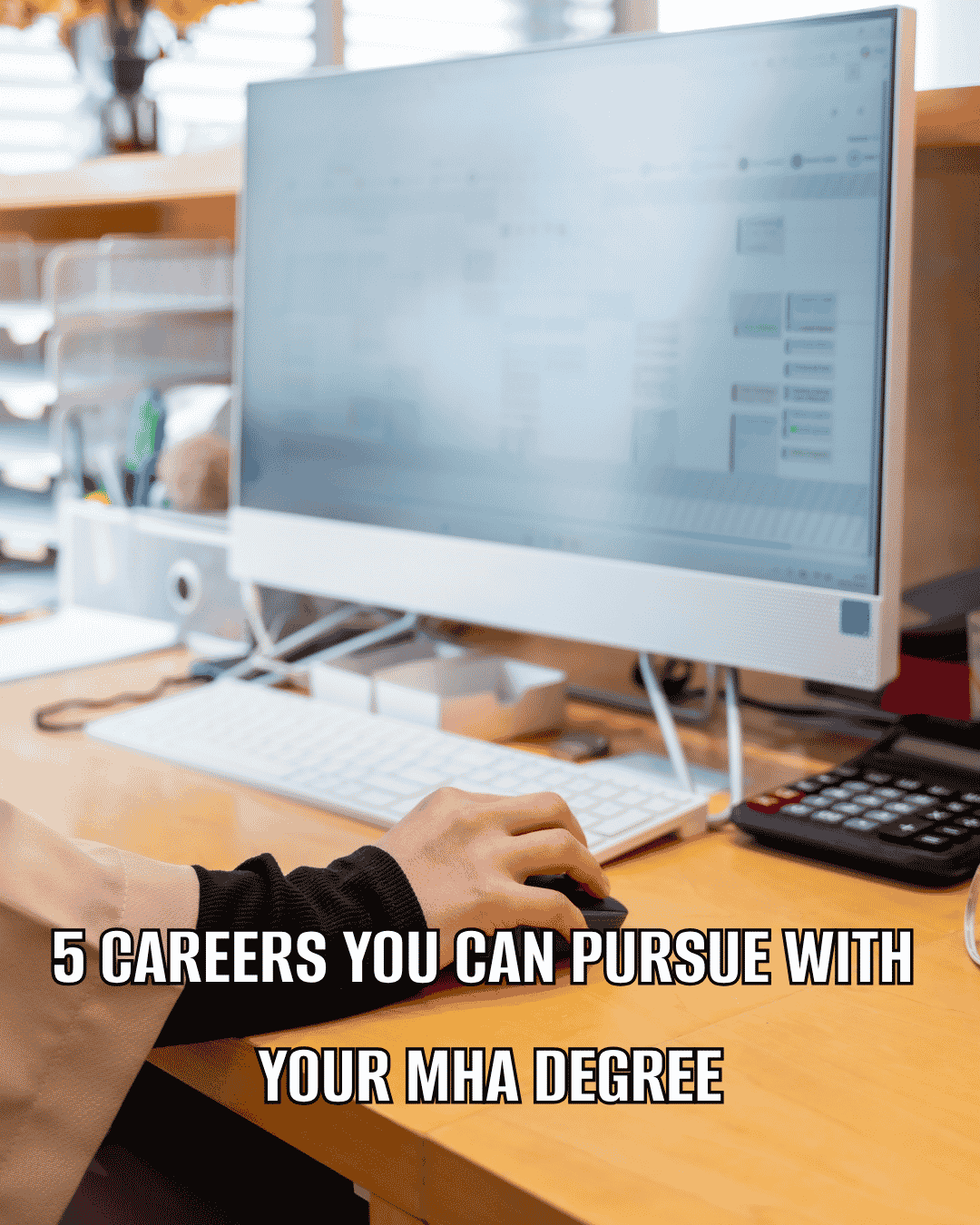 Person using a desktop computer at a desk with overlaid text reading “5 Careers You Can Pursue With Your MHA Degree.”