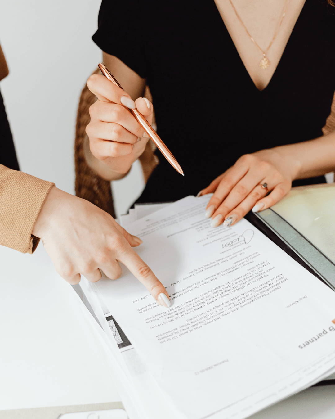 Person in black shirt looking over a folder with documents in it while holding a pencil. 